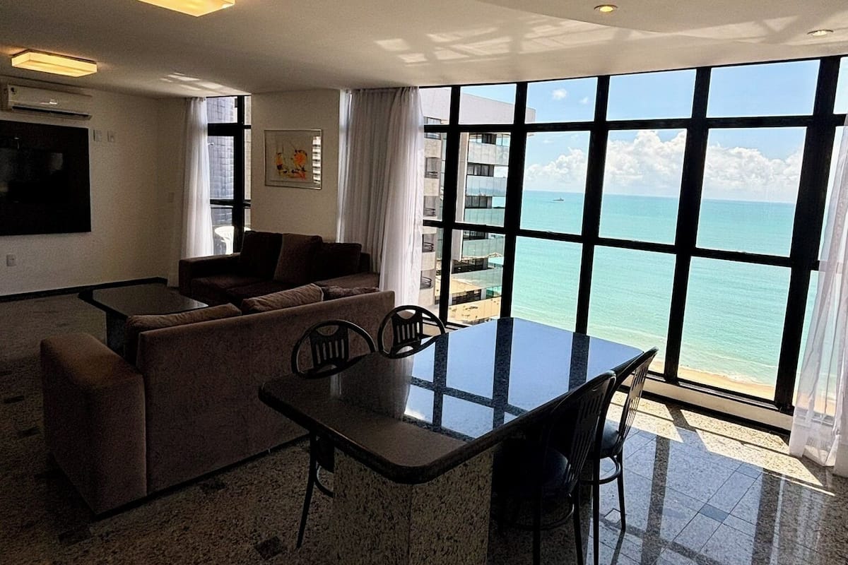 Una sala moderna con comedor, ventanas amplias y vista al océano.