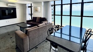 A modern hotel room with a living area, a dining table, and a large window offering a sea view. - Hotel Brasil Tropical (Fortaleza)