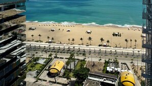 A high-rise hotel overlooking a beach with a clear view of the ocean and a parking area with yellow canopies. - Hotel Brasil Tropical (Fortaleza)