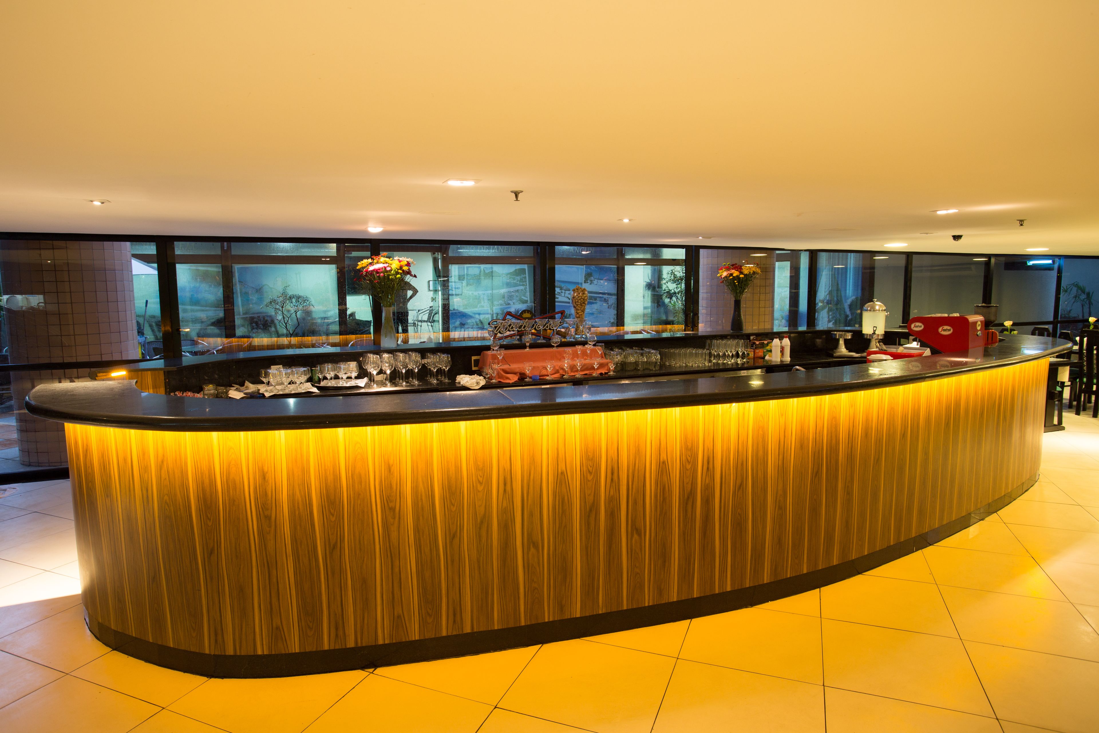 A modern bar area with a curved counter, large windows, and a view of the outside.