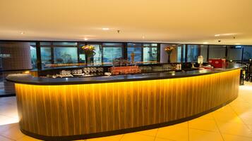 A modern bar area with a curved counter, large windows, and a view of the outside.