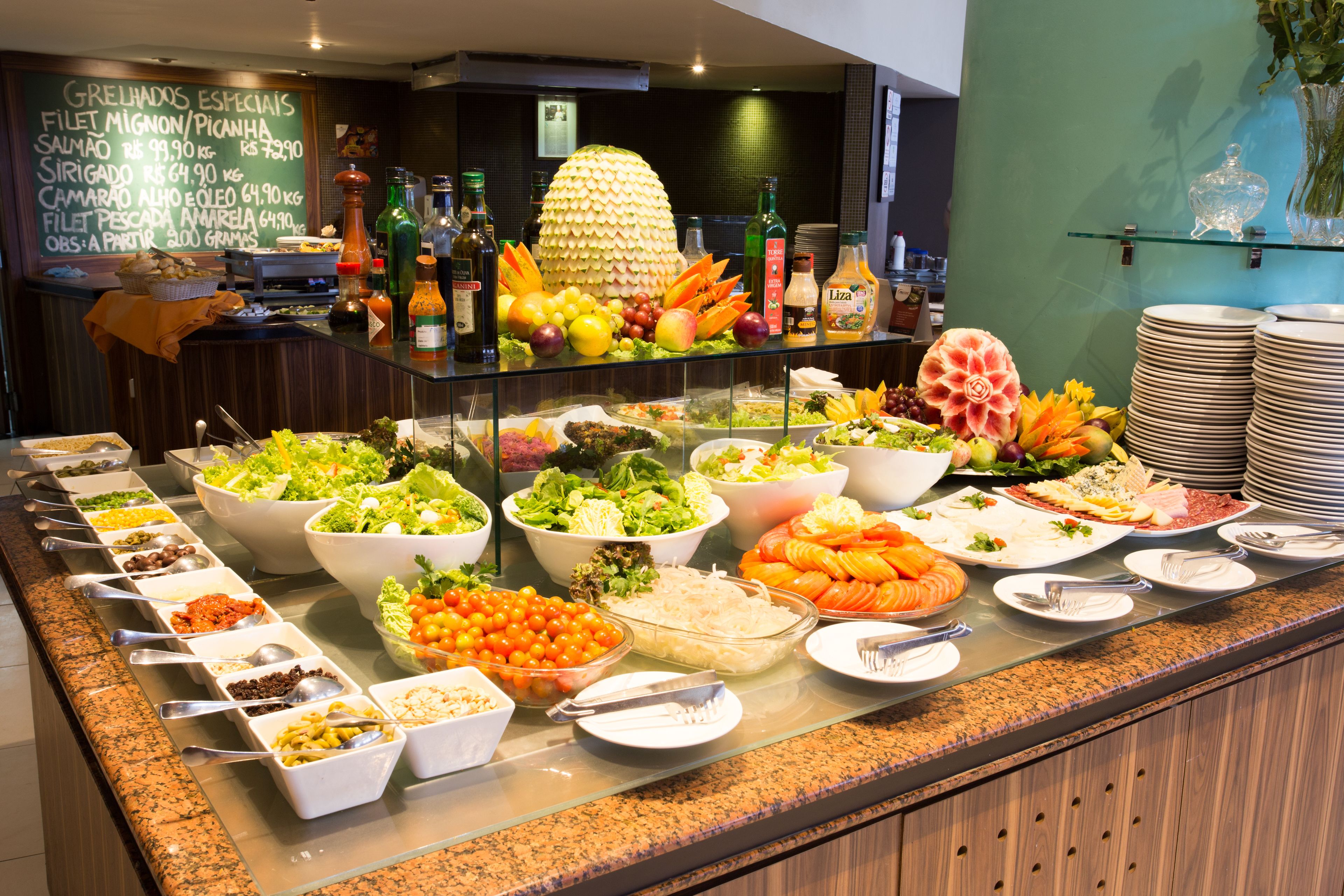 Buffet com diversos pratos e uma decoração central de abacaxi.