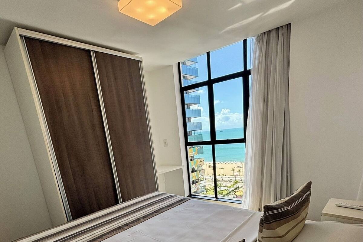 Una habitación de hotel con una cama grande, vistas a la playa y una puerta corredera.