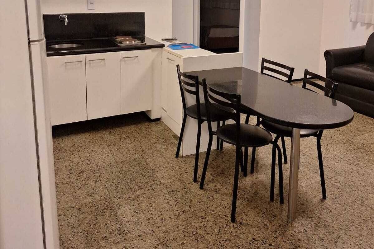 Una cocina pequeña con armarios blancos, una encimera negra y un ventanal de arco.