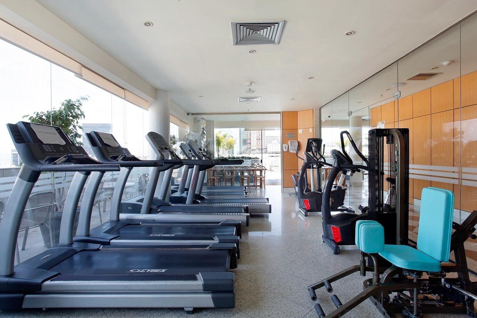 Een sportschool met loopbanden, elliptische trainers en een roeimachine.