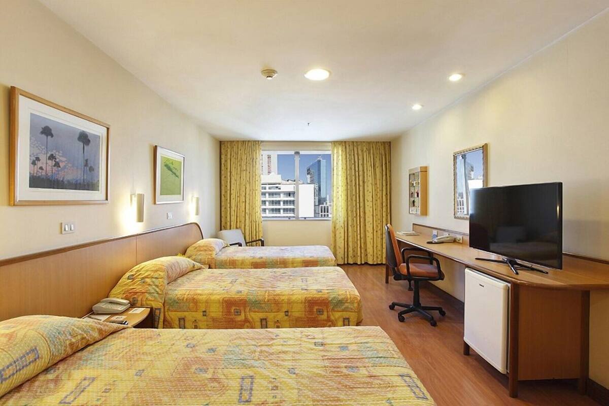 Hotelkamer met twee bedden, een bureau, een televisie en een raam met uitzicht op de stad.