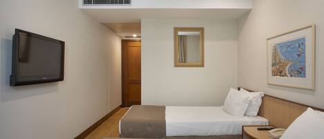 Habitación de hotel con dos camas, televisión, espejo y un cuadro en la pared.