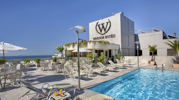 Zona de piscina con sillones de descanso y sombrillas en Windsor Hotels.