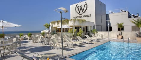 Alberca al aire libre, sombrillas en la alberca y camastros