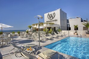 Un espace piscine avec des chaises longues et des parasols dans les hôtels Windsor.
