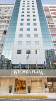 A hotel with a modern glass facade, a visible entrance, and multiple flags.