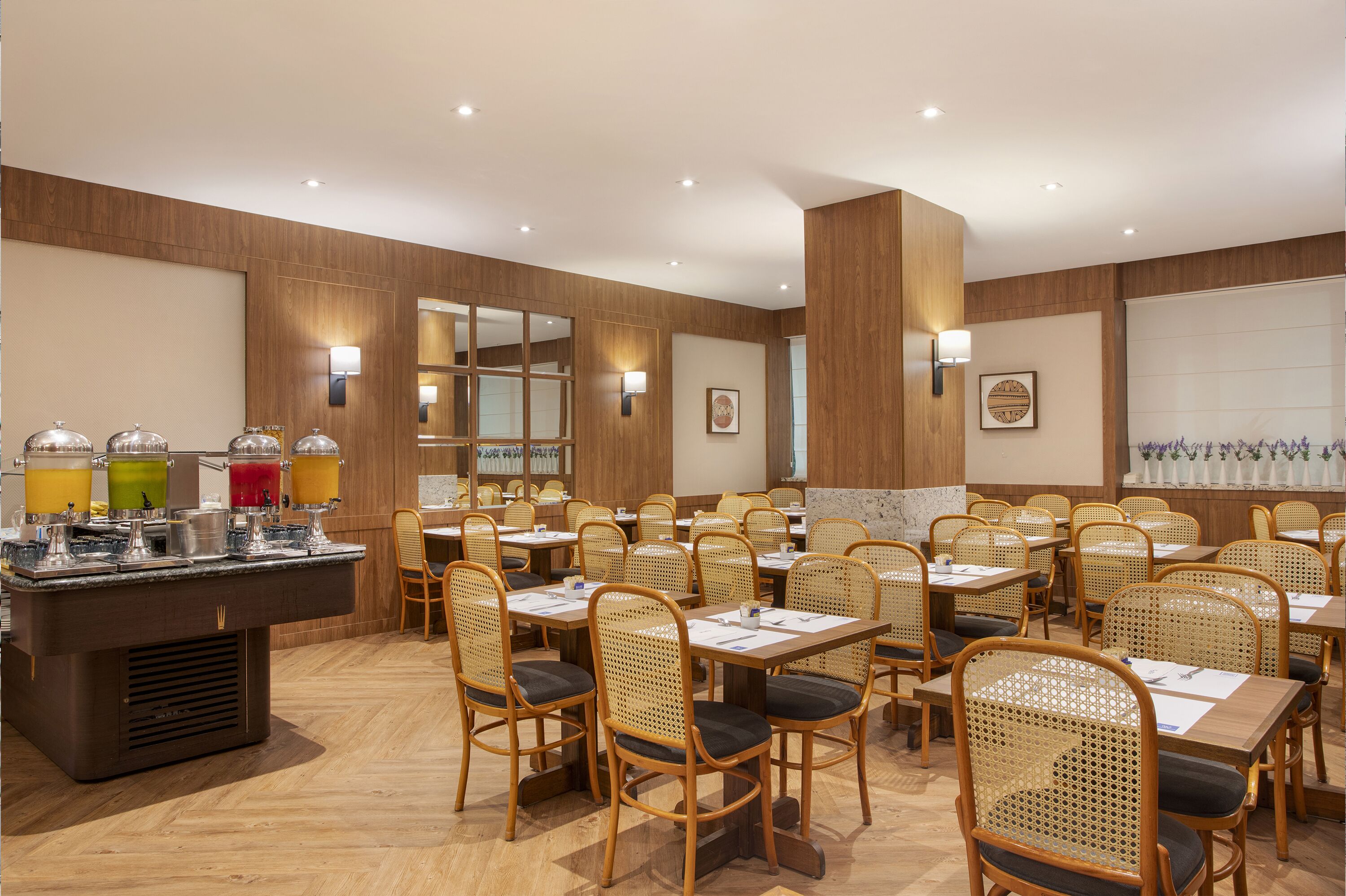 Une salle à manger d’hôtel avec des murs en bois, un buffet proposant divers plats et des chaises en osier.