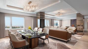 Ein modernes Hotelzimmer mit Essbereich, einer Sofagarnitur und einem großen Fenster mit Blick auf die Stadt.