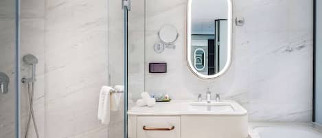 A modern bathroom with a glass shower enclosure, a white sink with a mirror above it, and a bathtub.
