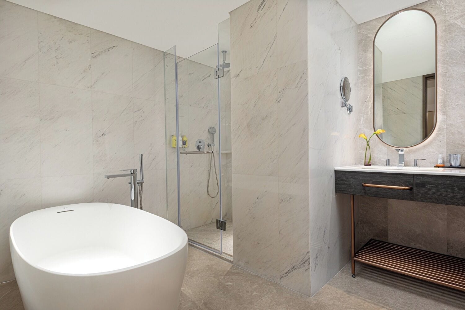 Un baño moderno con una bañera independiente, ducha con mampara de vidrio y tocador con espejo.