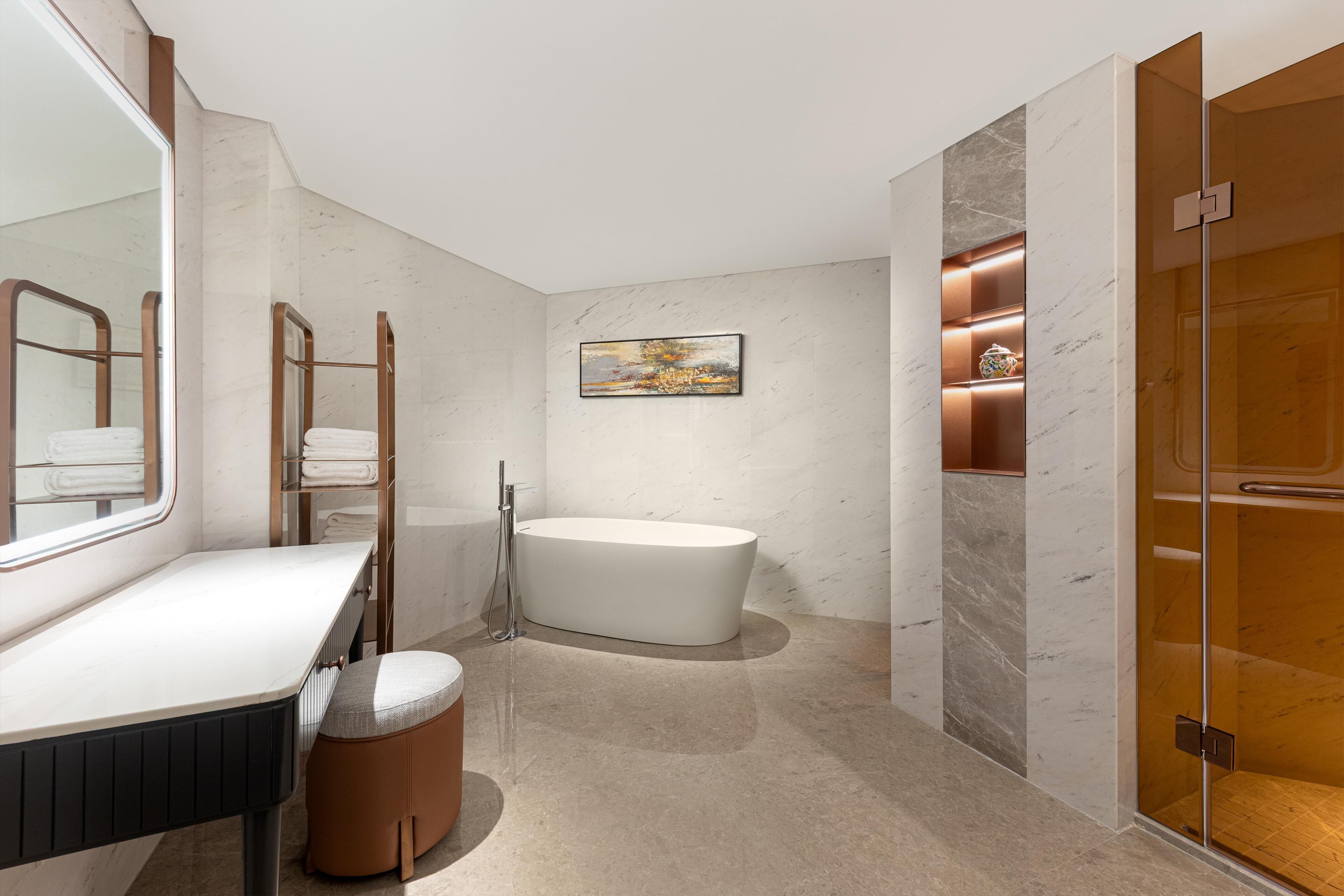 Un baño moderno con una bañera independiente, un tocador con espejo y una zona de ducha con mampara de vidrio.