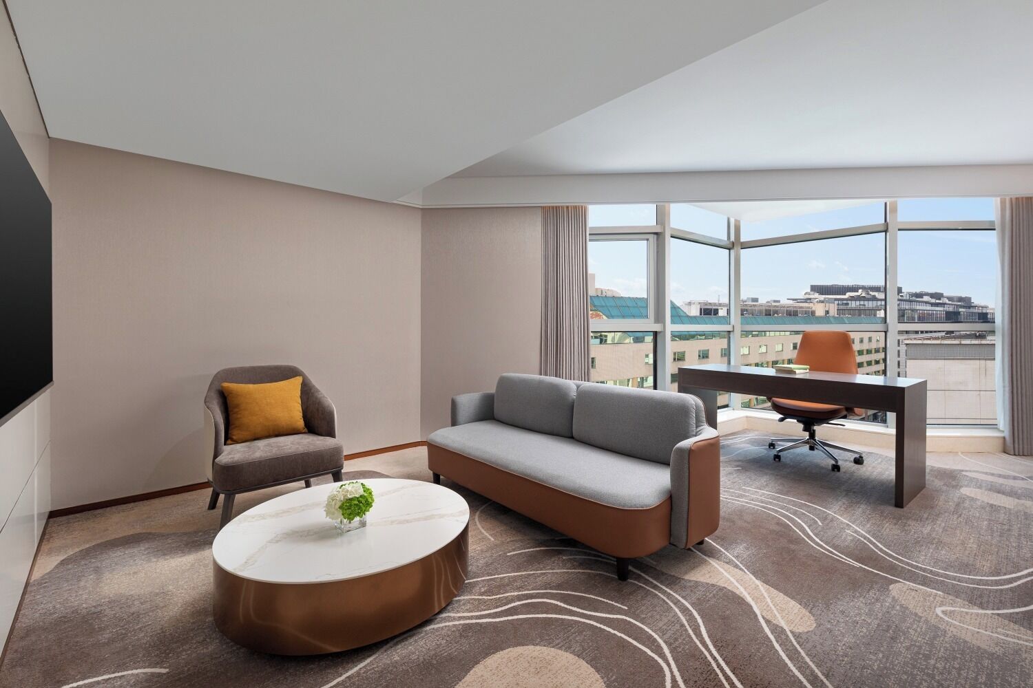 Une chambre d’hôtel moderne, équipée d’un canapé, d’un fauteuil et d’un bureau.