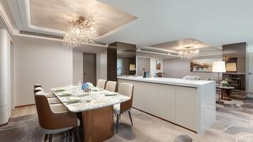 A modern hotel room with a dining area, a kitchen, and a living area.