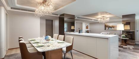A modern hotel room with a dining area, a kitchen, and a living area.
