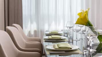 Una mesa de comedor dispuesta con platos, vasos y un jarrón de flores.