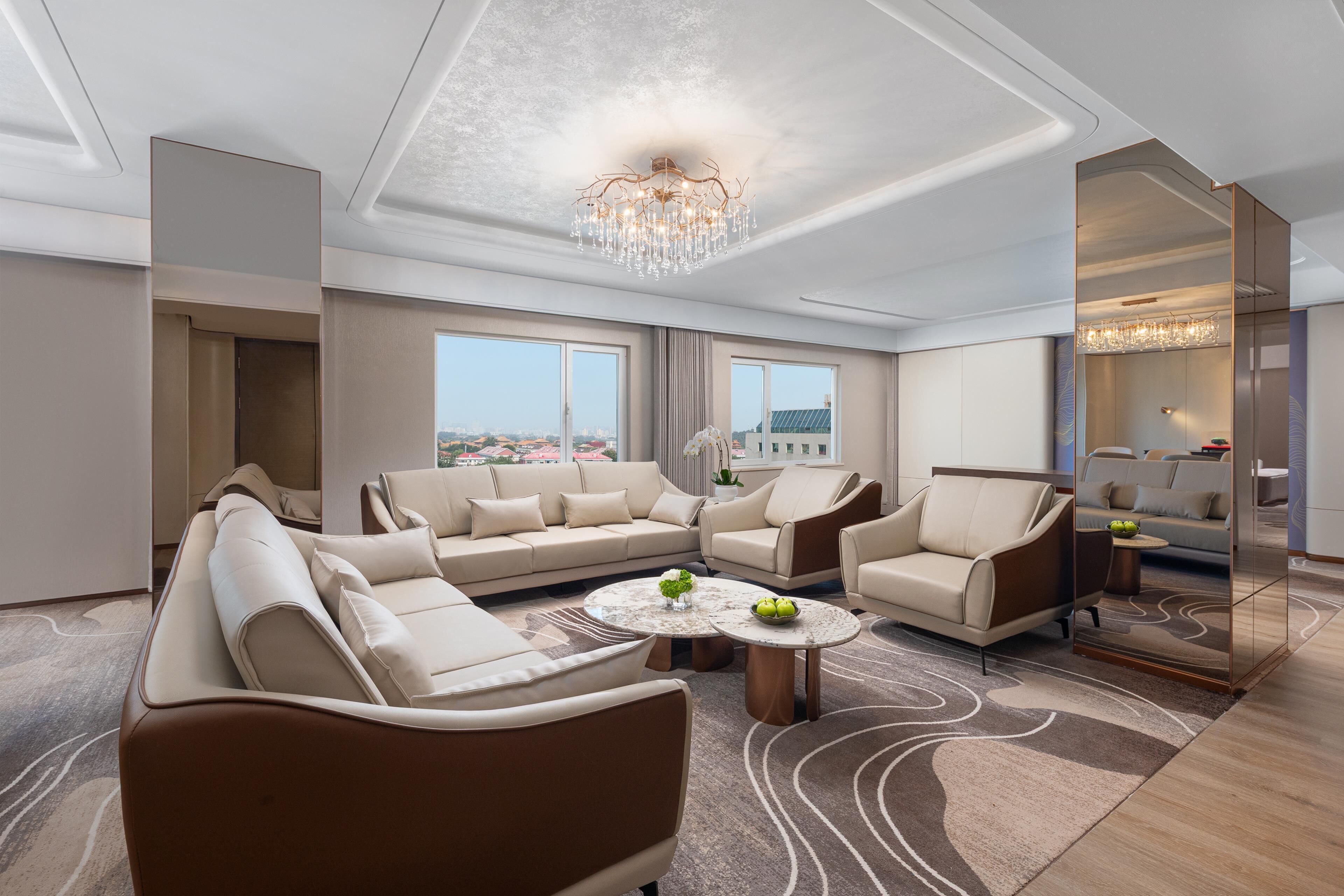 A spacious living room with a large sofa, armchairs, a coffee table, and a chandelier.