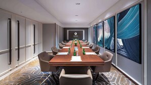 Ein Konferenzraum mit einem langen Tisch, Stühlen und einem großen Fenster mit Kunstwerken.