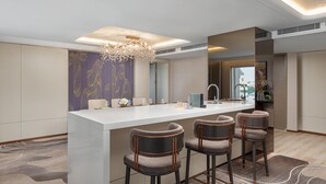 A modern kitchen with a central island, bar stools, and a decorative chandelier.