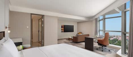 A modern hotel room with a large bed, a desk, and a TV.