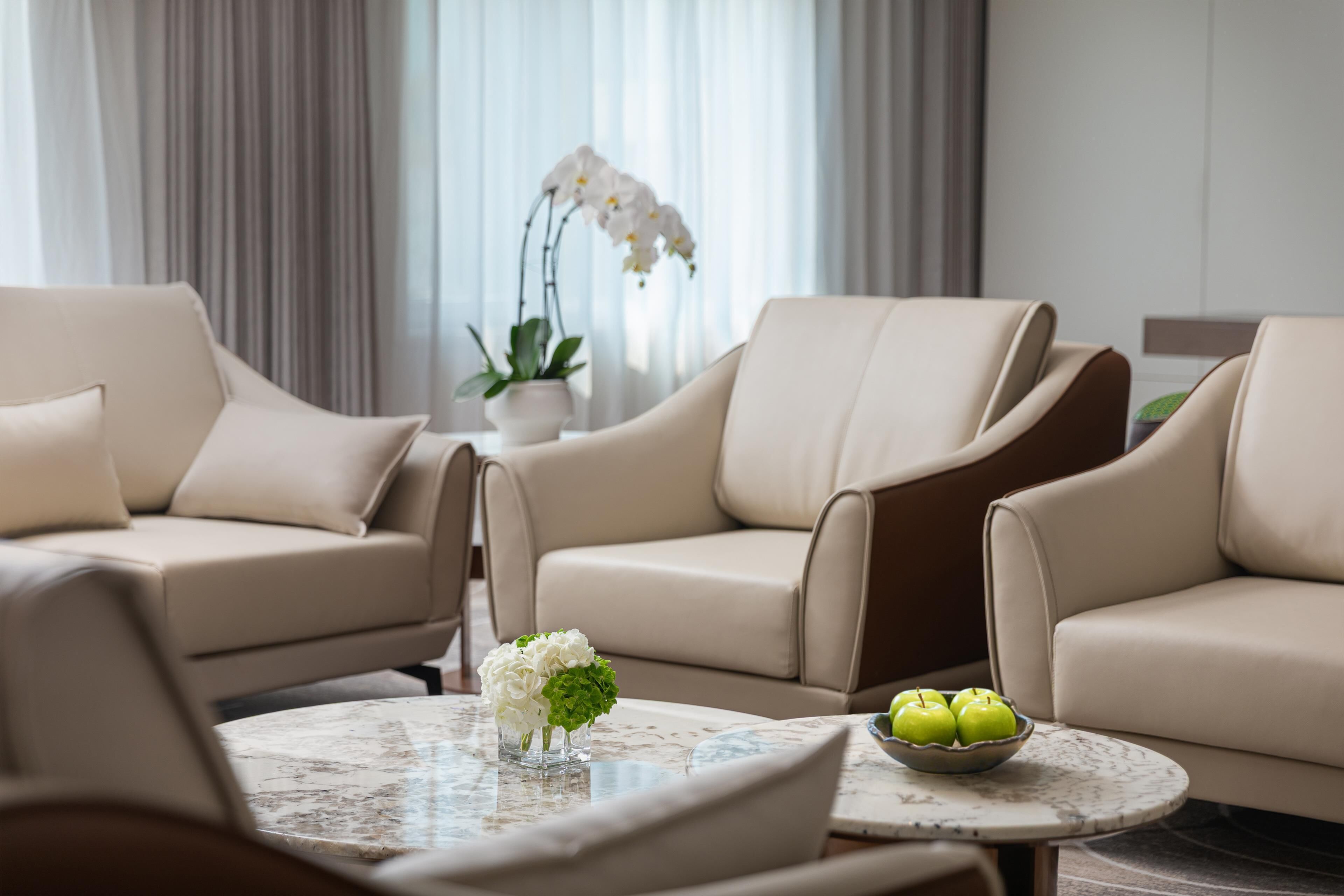 A modern living room with two beige sofas, a round coffee table, and a potted orchid.