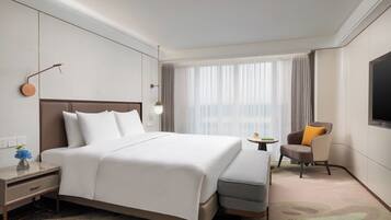 A modern hotel room with a large bed, a small round table, a chair, and a TV.