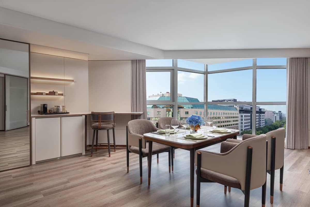 A modern dining area with a large window, a kitchen with a bar, and a city view.