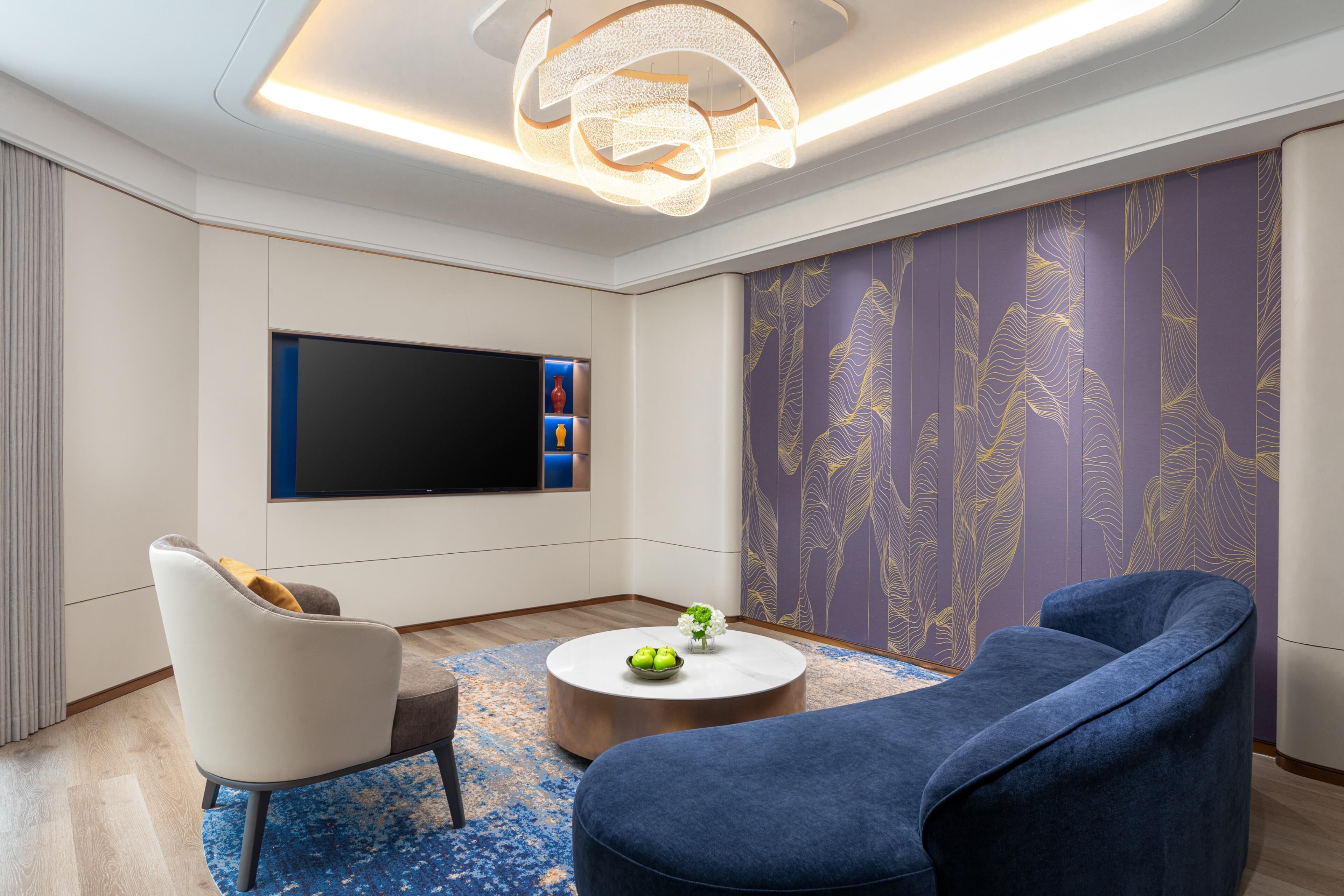 Een moderne woonkamer met een flatscreen televisie, comfortabele zitplaatsen en een decoratieve wand.