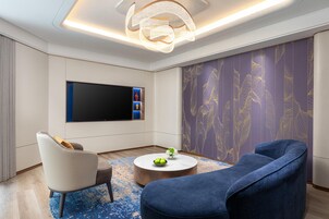 A modern living room with a flat-screen TV, comfortable seating, and a decorative wall.