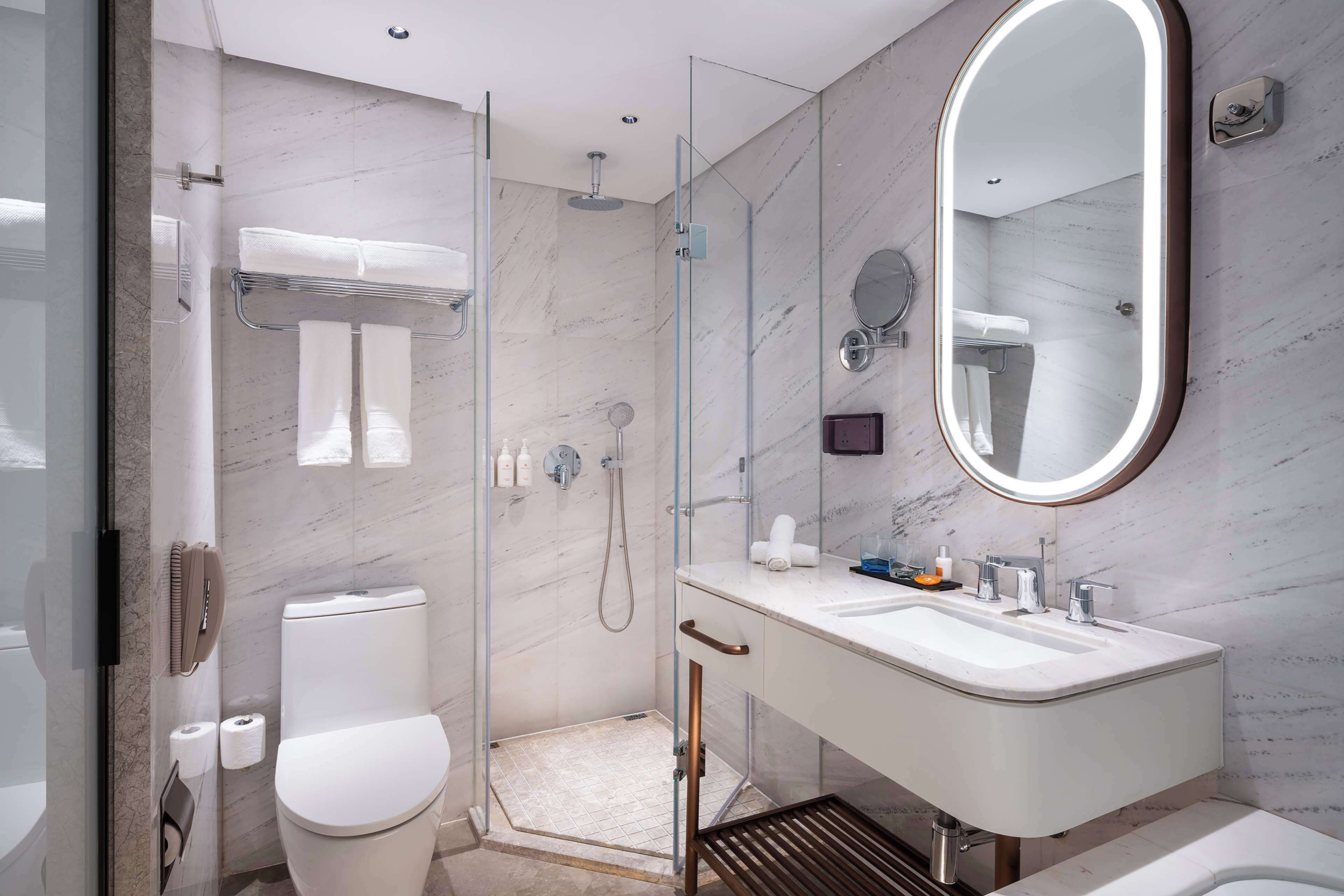 A modern bathroom with a glass-enclosed shower, a white sink, and a large mirror.