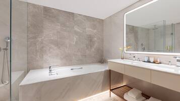 A modern bathroom with a marble bathtub, a large mirror, and a walk-in shower.