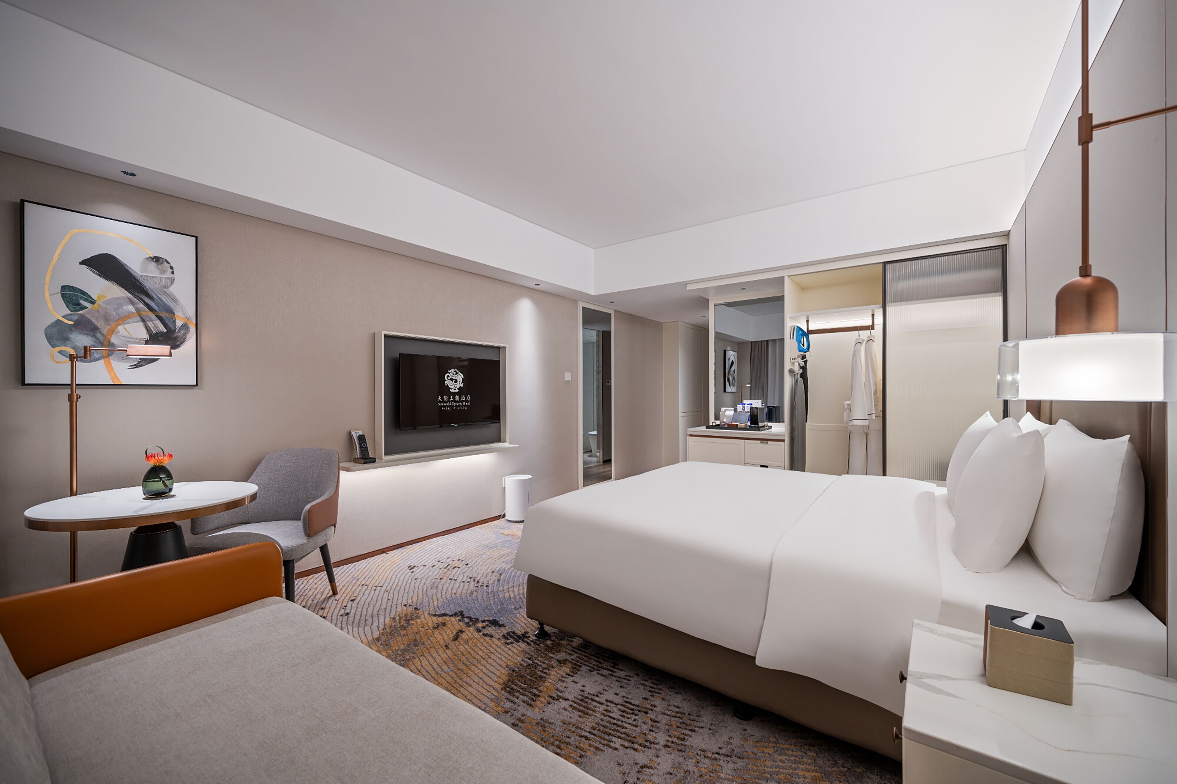 Et moderne hotelværelse med seng, skrivebord, stol, fjernsyn og et spejl.