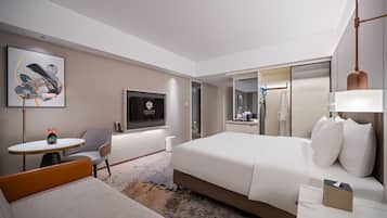Une chambre d’hôtel moderne équipée d’un lit, d’un bureau, d’une chaise, d’une télévision et d’un miroir.