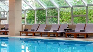 Ein Schwimmbecken mit Liegestühlen und einer Glaskuppel.