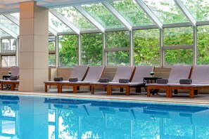 A swimming pool with lounge chairs and a glass ceiling. - Sunworld Dynasty Hotel Beijing Wangfujing (Beijing)