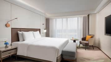 Une chambre d’hôtel avec un grand lit, un bureau avec une lampe, une chaise et un téléviseur fixé au mur.