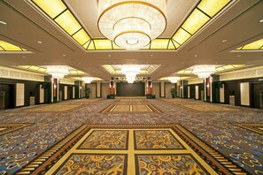 A spacious hall with a patterned carpet, chandeliers, and a large chandelier on the ceiling.
