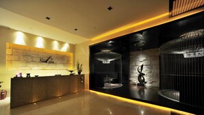 A modern reception area with a stone wall, a reception desk, and a large chandelier.