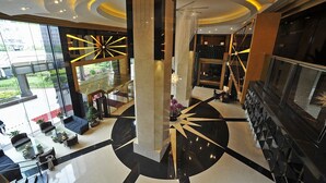A modern lobby with a central column, seating area, and a staircase.