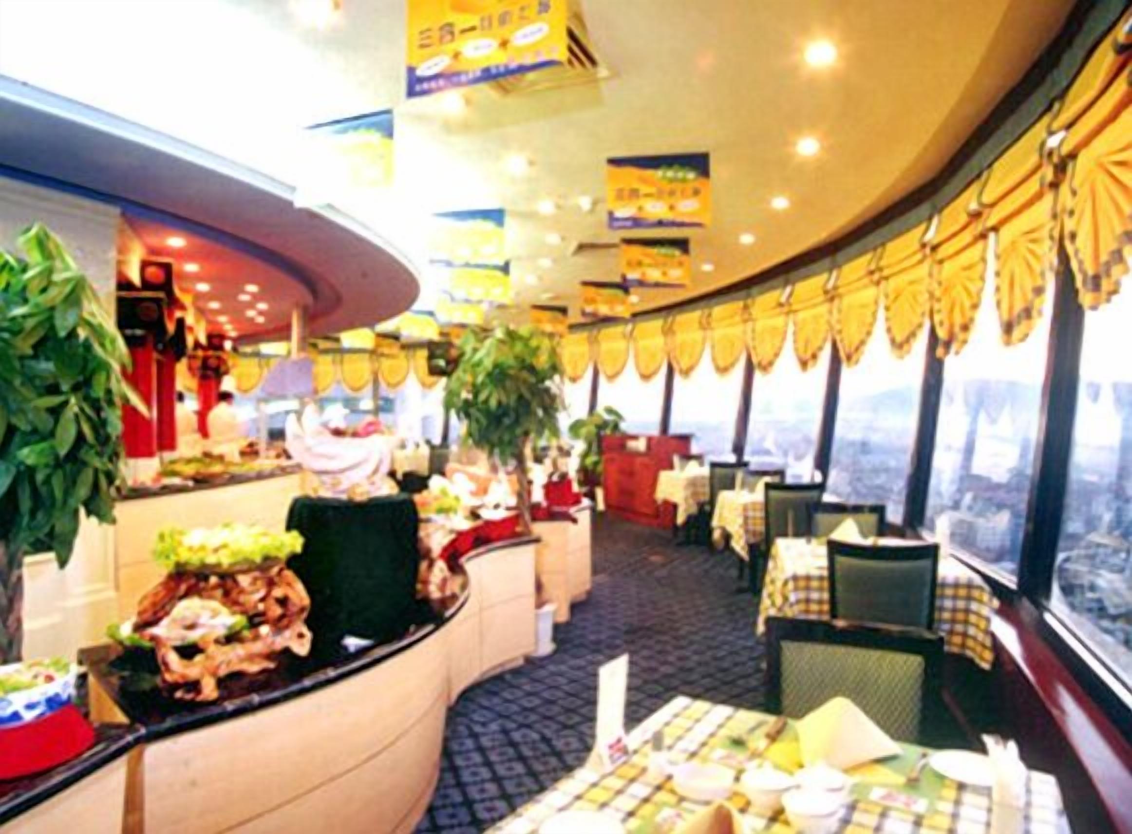 A restaurant with a curved layout, large windows, and a variety of seating arrangements.