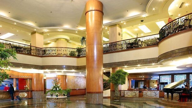 A spacious lobby with a grand piano, multiple levels with balconies, and a central column. - Gloria Plaza Hotel Shenyang (Shenyang)