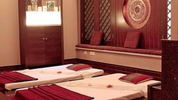 A spa room with two massage beds, a mirror, and a decorative wall.