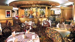 A restaurant with round tables, chairs, and a central bar area. - Gloria Plaza Hotel Shenyang (Shenyang)
