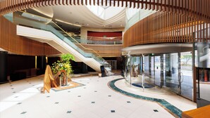 Ein geräumiges Atrium mit einer zentralen Treppe, Glasgeländern und einem modernen Design.
