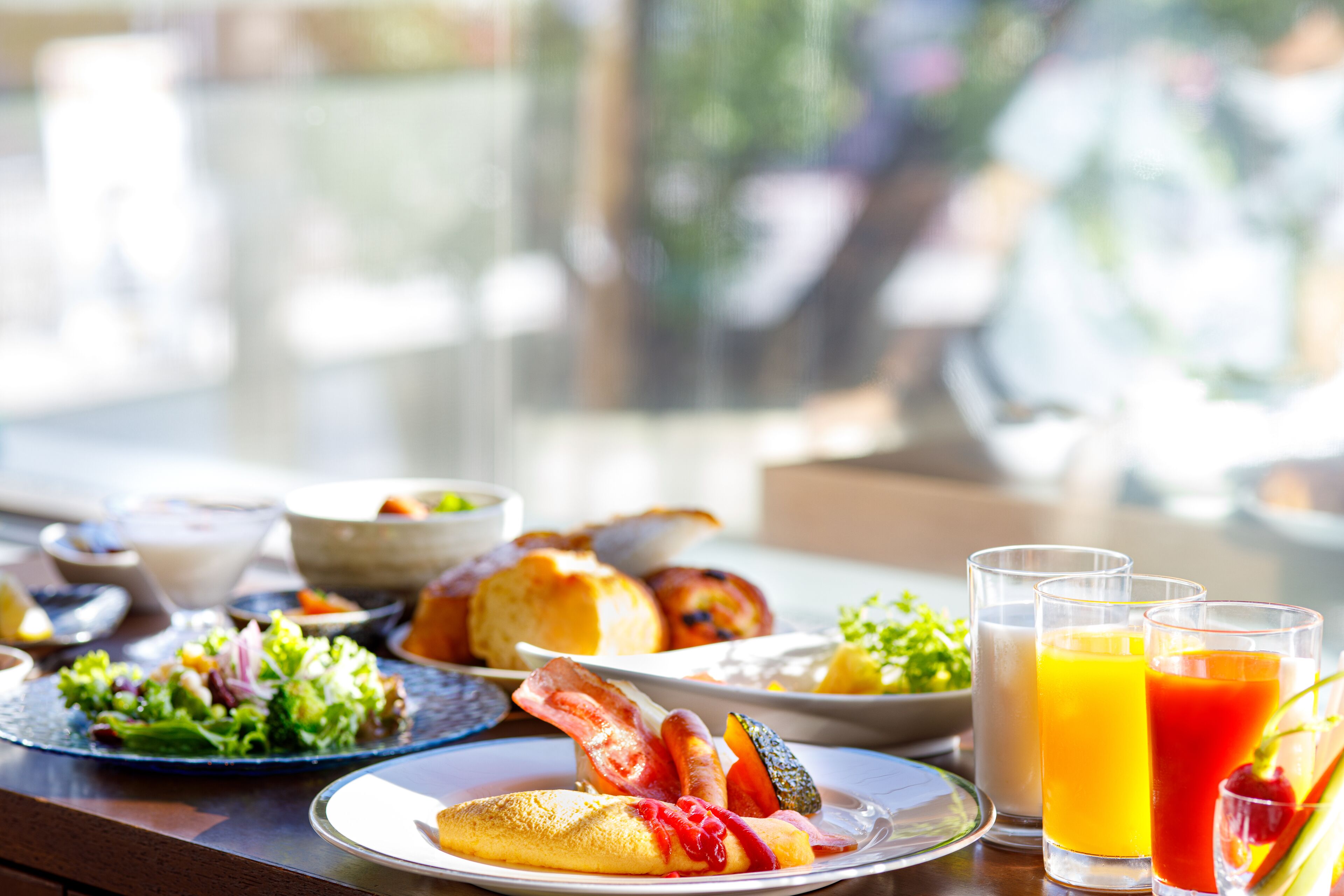 A breakfast table with various dishes, including eggs, bacon, and toast, along with glasses of orange juice.