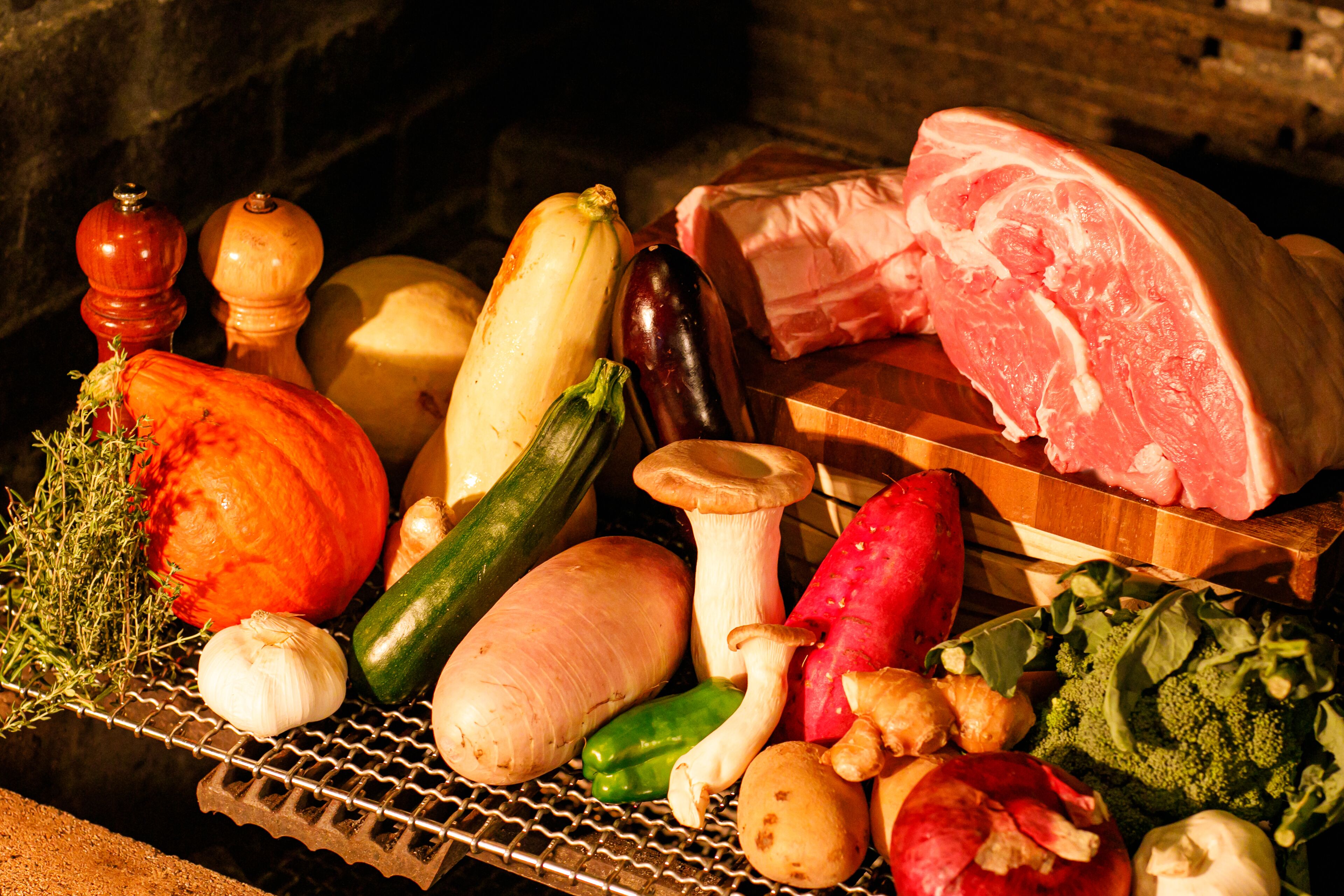A variety of fresh vegetables and meats displayed on a wire rack.